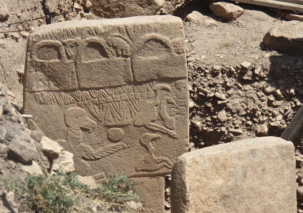 Pilar 43 de Göbekli Tepe com animais esculpidos e três formas retangulares arqueadas na parte superior.